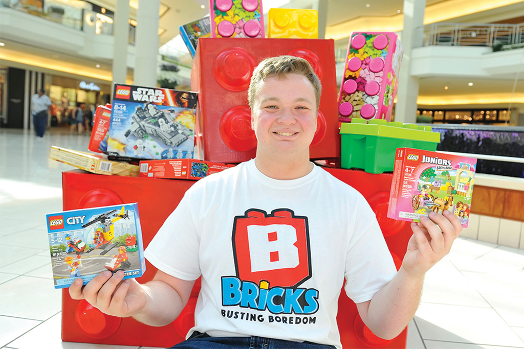 An image of a man holding boxes of legos for Bricks Busting Boredom, a non-profit based out of Wellington, FL.
