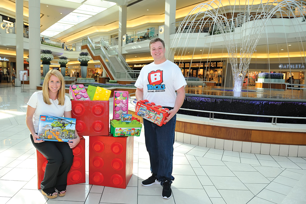 An image of a man and women standing with boxes of legos for Bricks Busting Boredom, a non-profit based out of Wellington, FL.